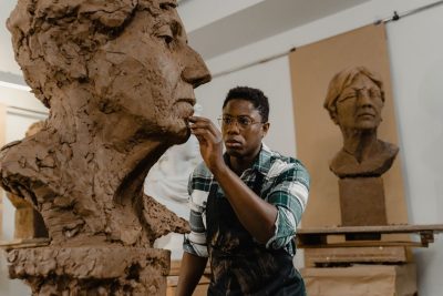 ""sculptor working on a large clay bust in art studio