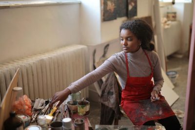""young artist leaning over to grab a paint brush