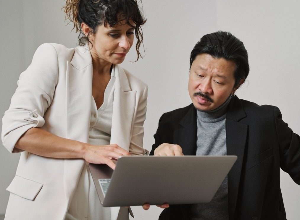 Two colleagues reviewing a presentation together on a laptop