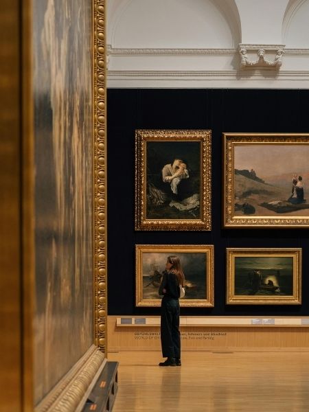 Visitor viewing framed paintings on gallery walls, representing the digital assets institutions manage with TMS Media Studio.