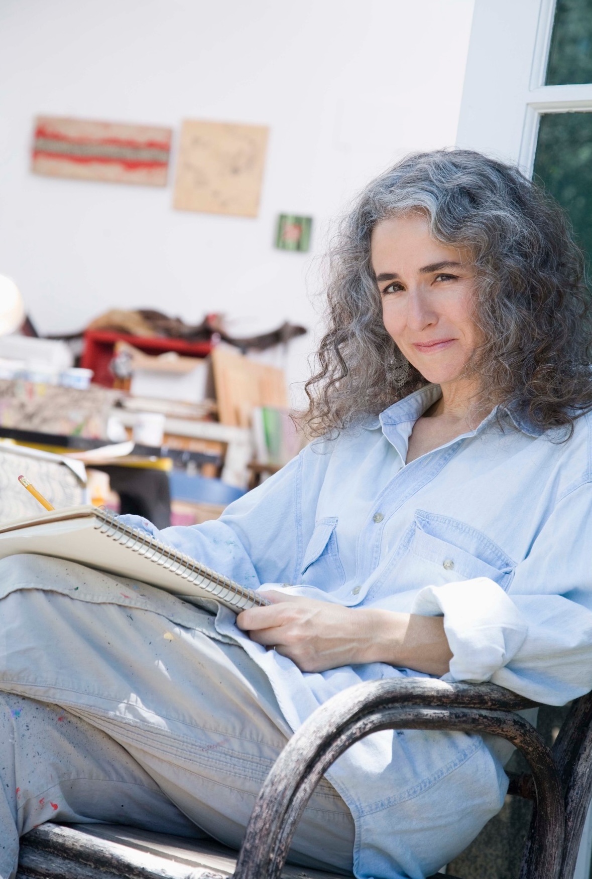 artist sitting in her studio drawing on a big drawing pad.