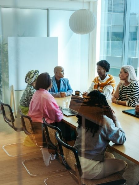 A diverse collections team in discussion around a conference table, collaborating on collections data and workflow strategy