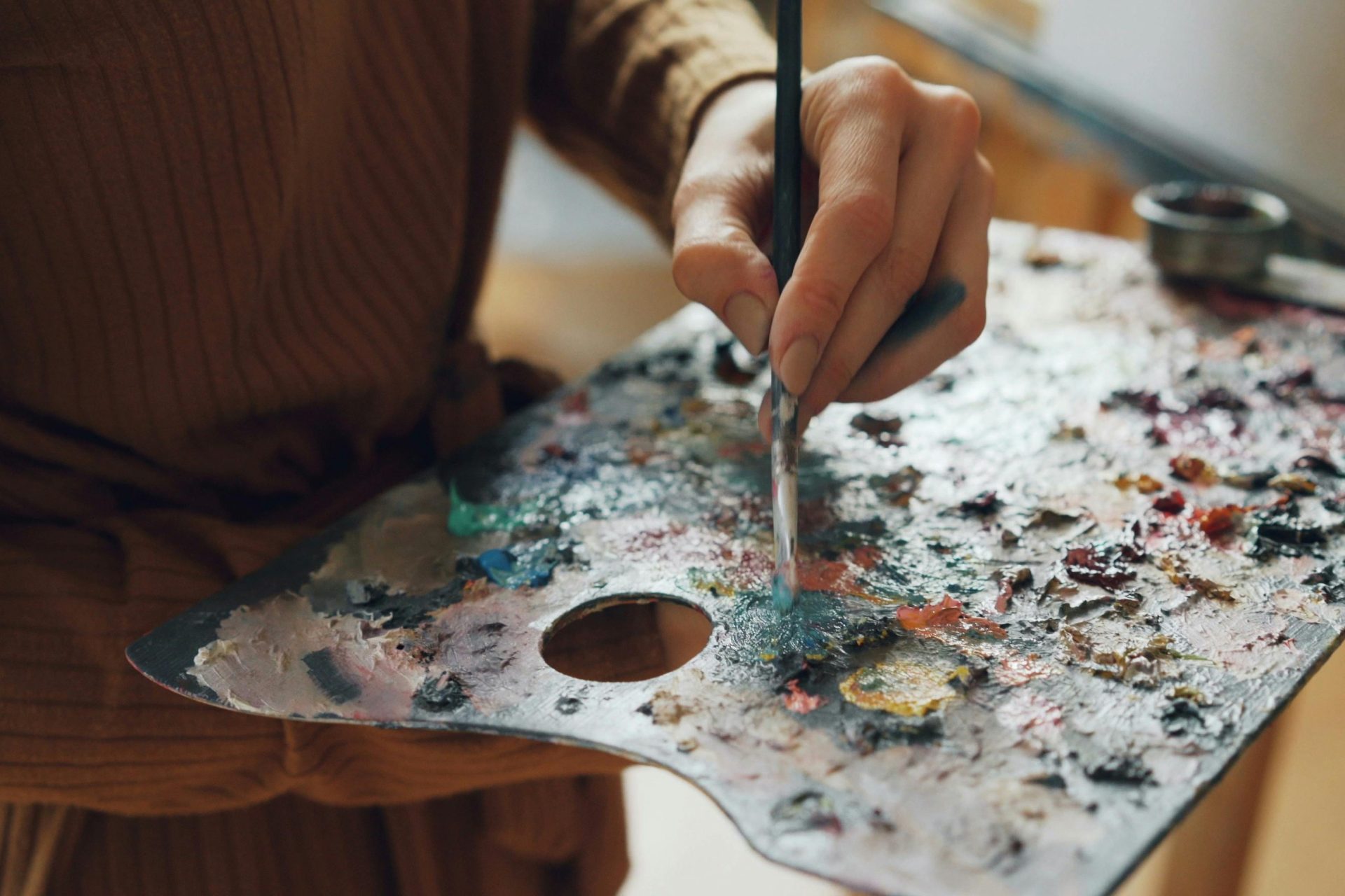 an artist mixing paint on a palette.