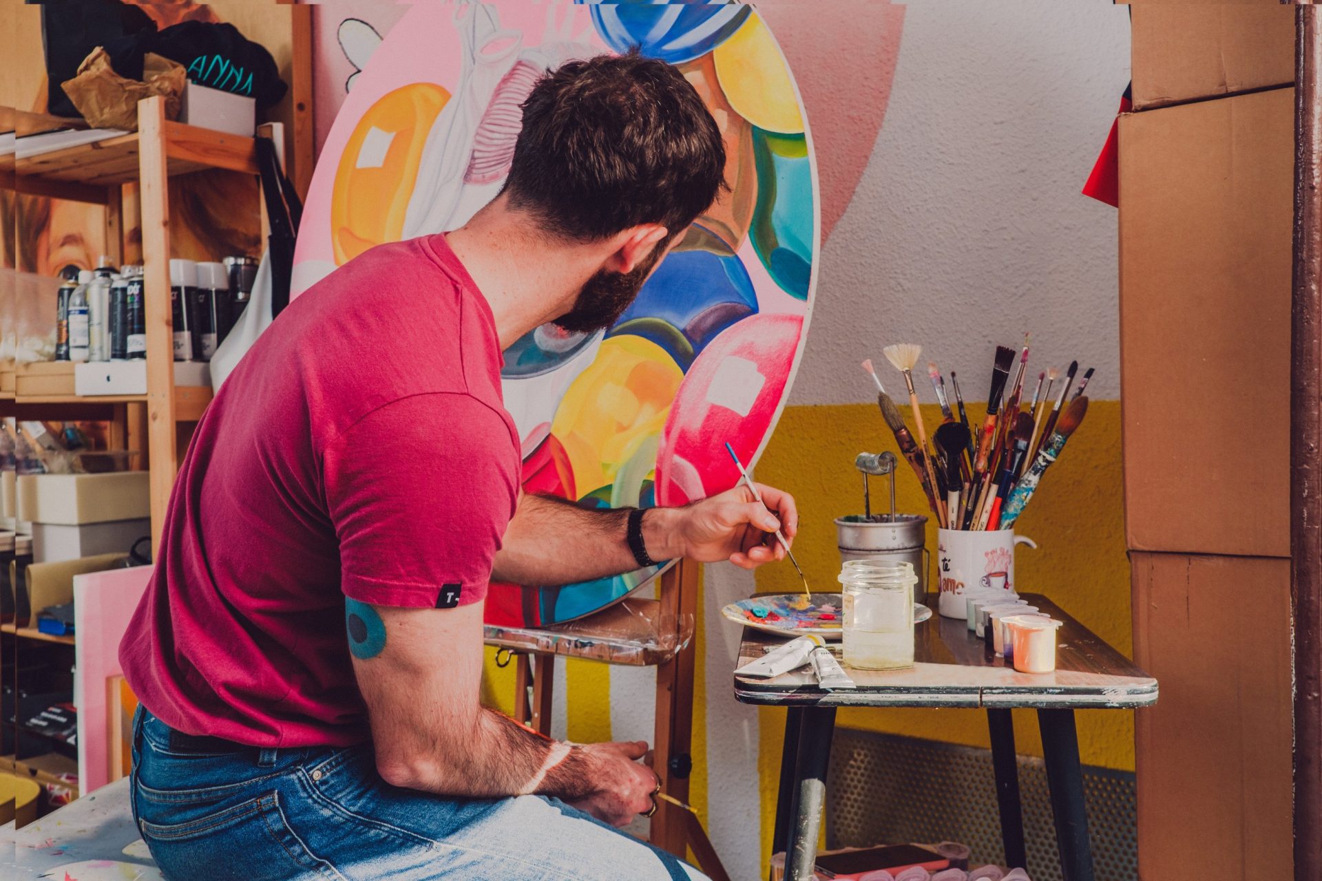 painter sitting at his easel painting in bright colors.