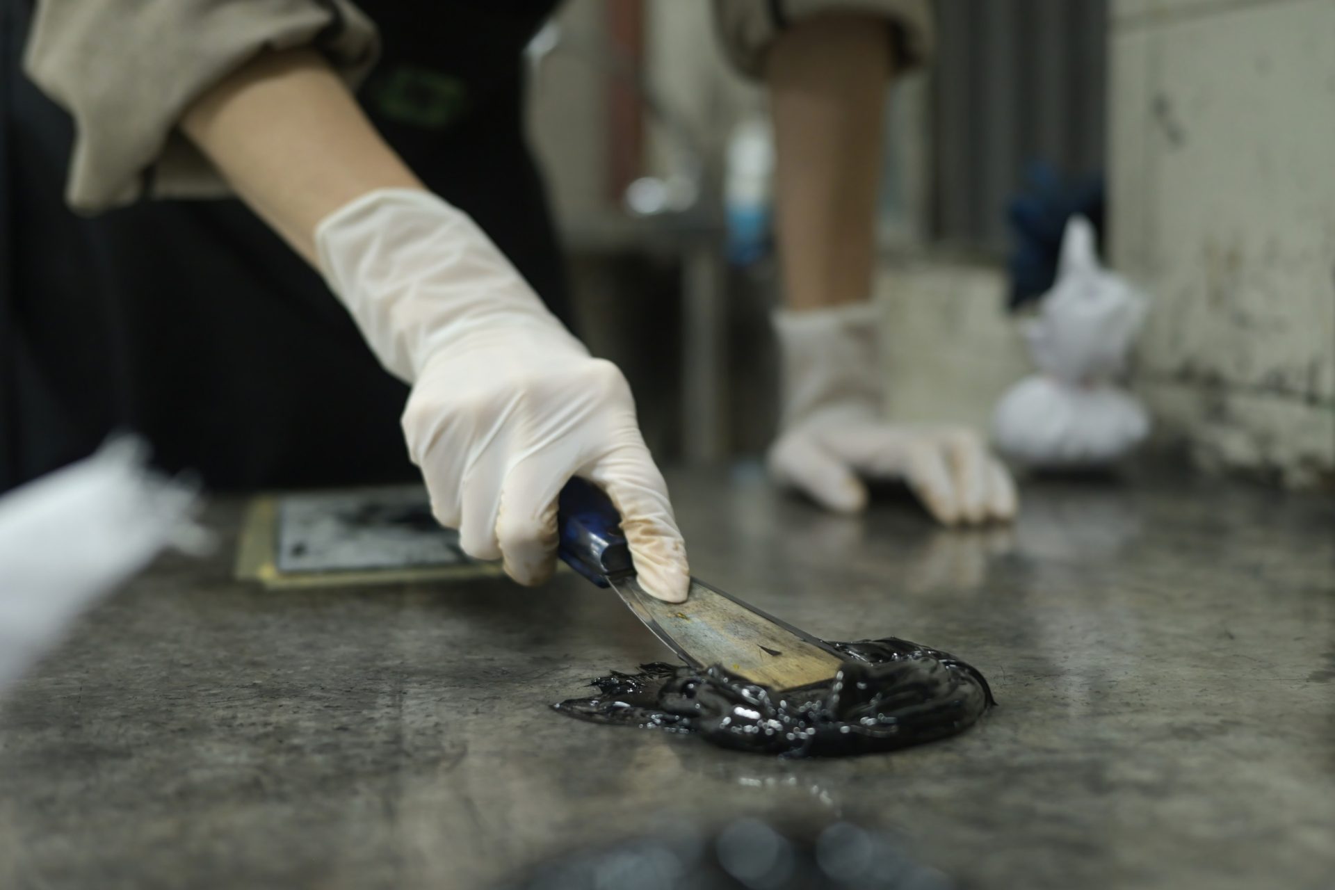 printmaker mixing black pigment in print studio.