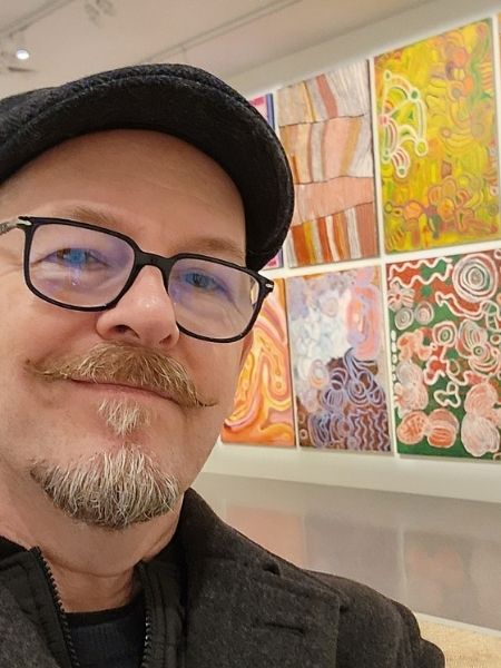 Dimitry Vesensky pausing beside vibrant contemporary artwork during a gallery visit.