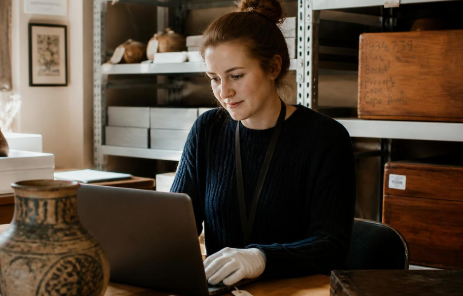 A gloved staff member working on a laptop in collections storage, reflecting the careful protection of sensitive collections data.