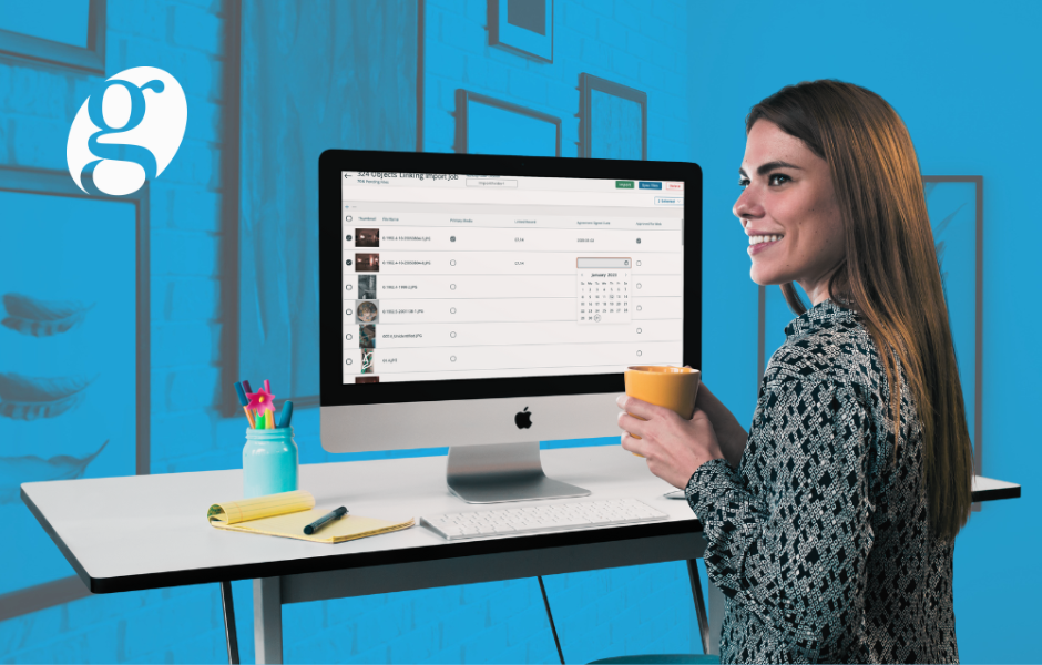 A brunette woman holding a cup of coffee and smiling. TMS Media Studio is on the desktop computer in front of her.